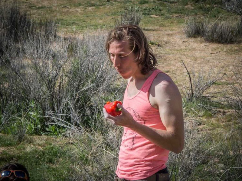 NAte Lapinski (shunt) eating an apple in a field with a pink tank top.